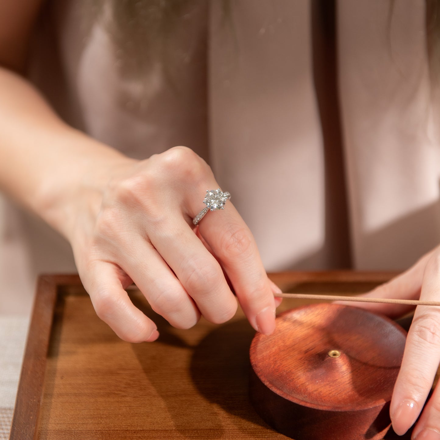 Person using chopsticks to pick up a small object from a wooden tray.