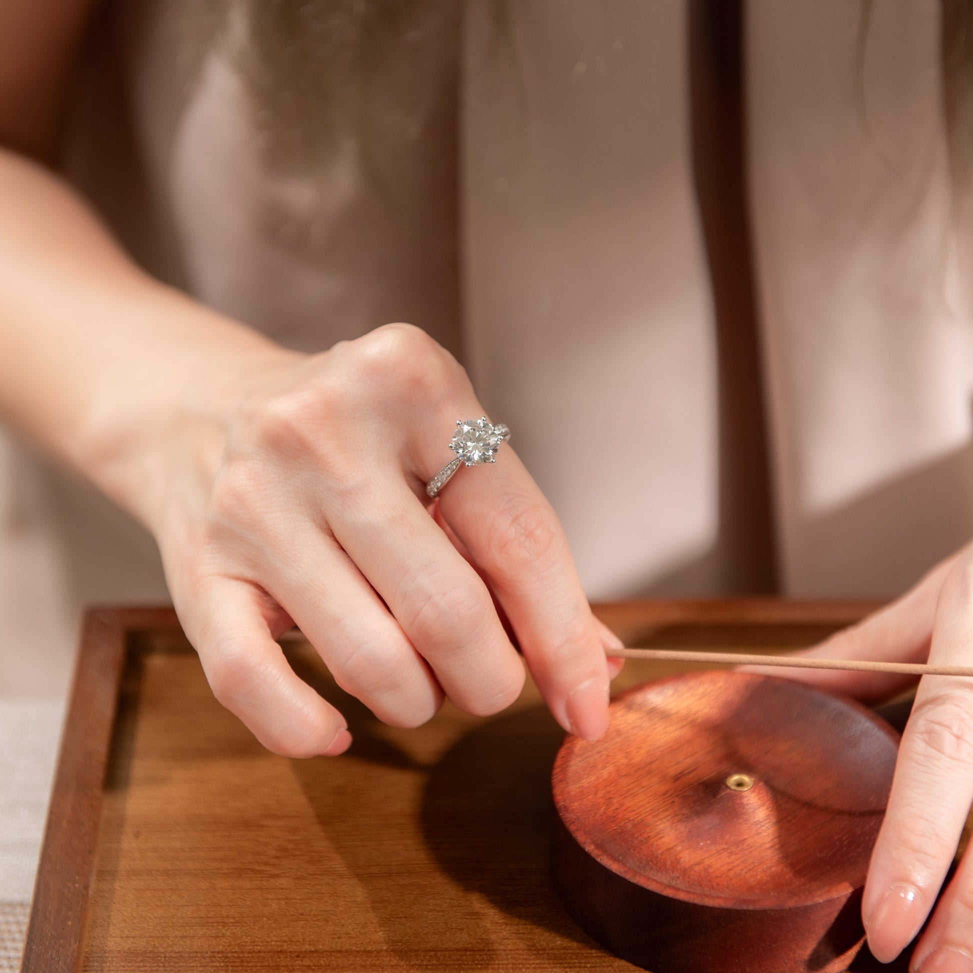 Person using chopsticks to pick up a small object from a wooden tray.