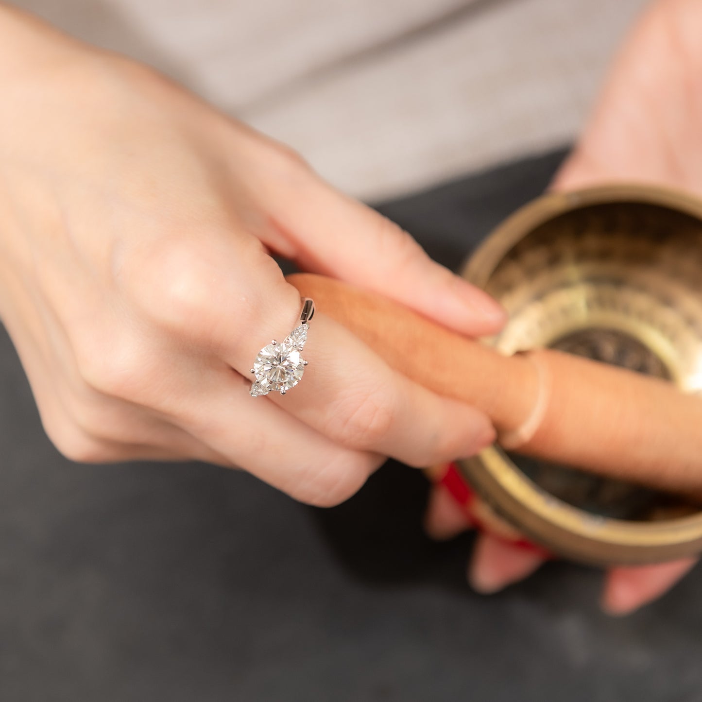 Close-up of a hand wearing a diamond ring with a blurred background