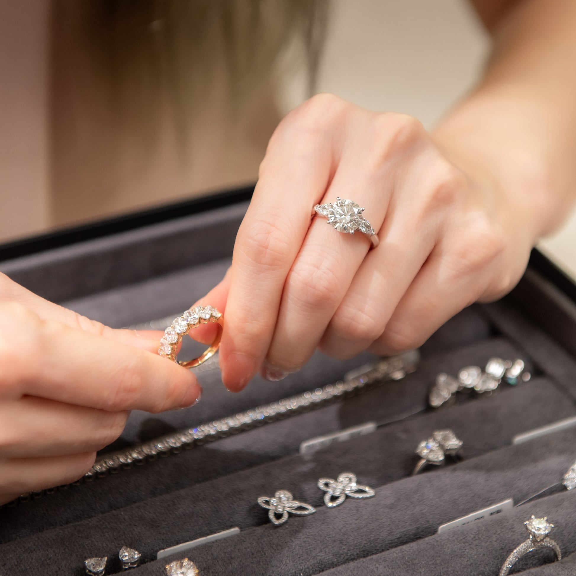 Person examining diamond rings in a jewelry box