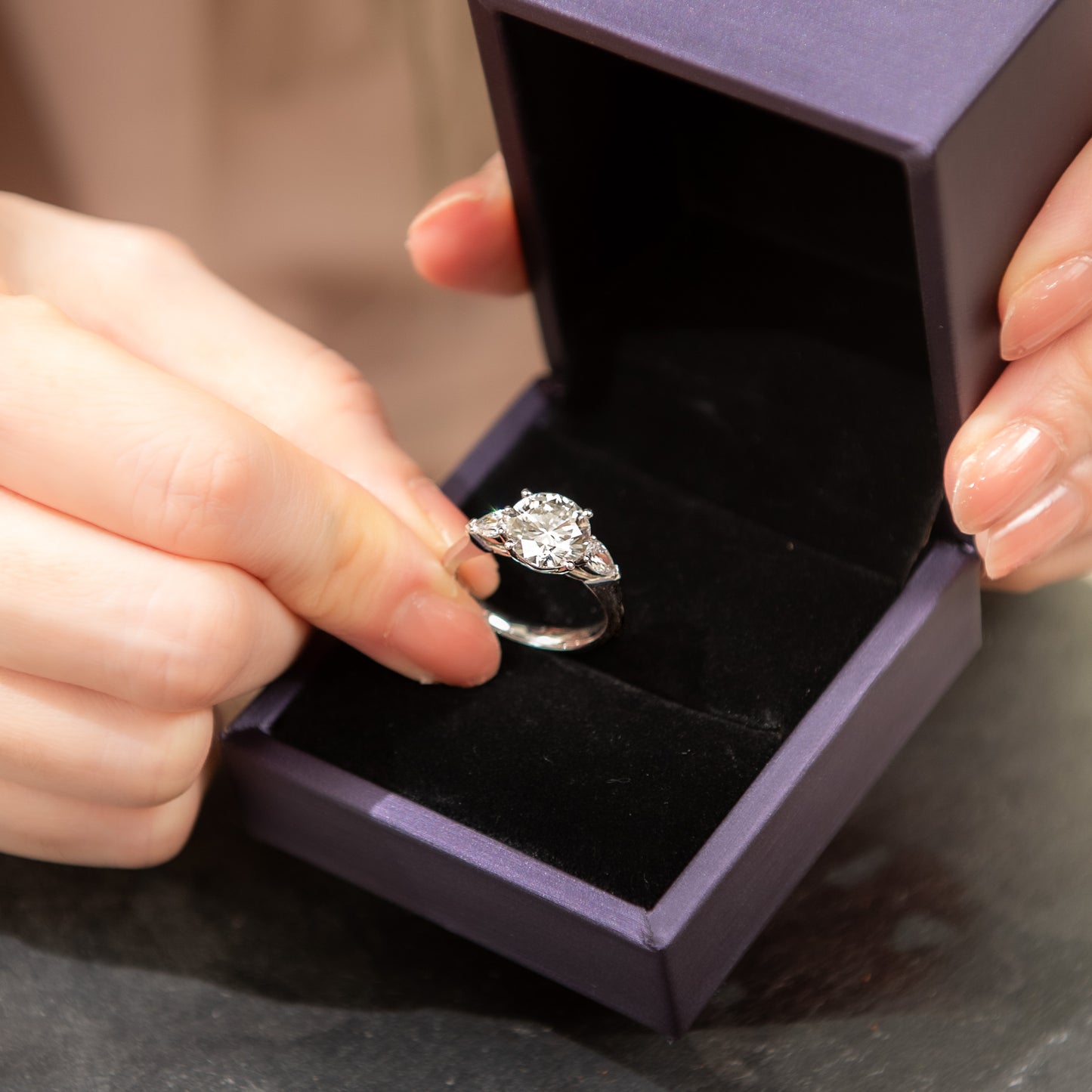 Diamond ring in a purple box held by hands