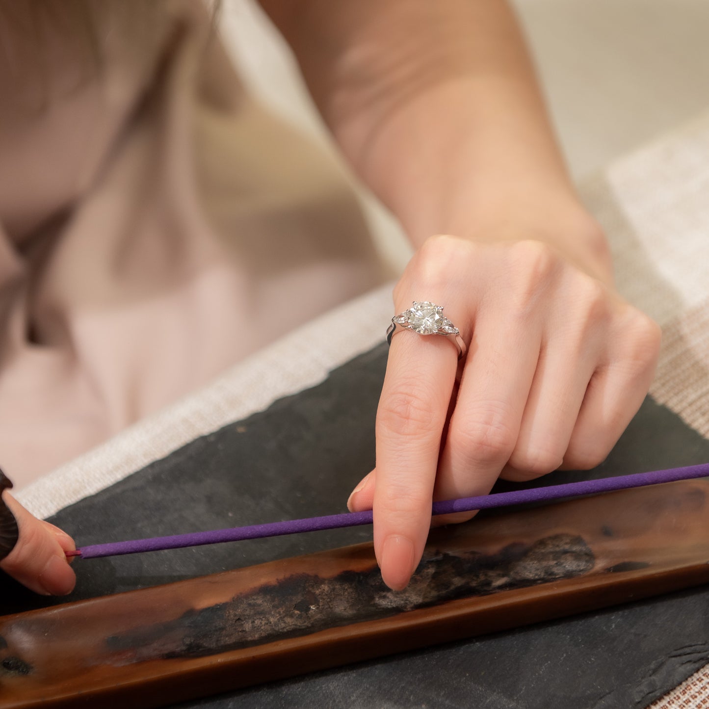Person holding a purple string over a wooden surface with a blurred background