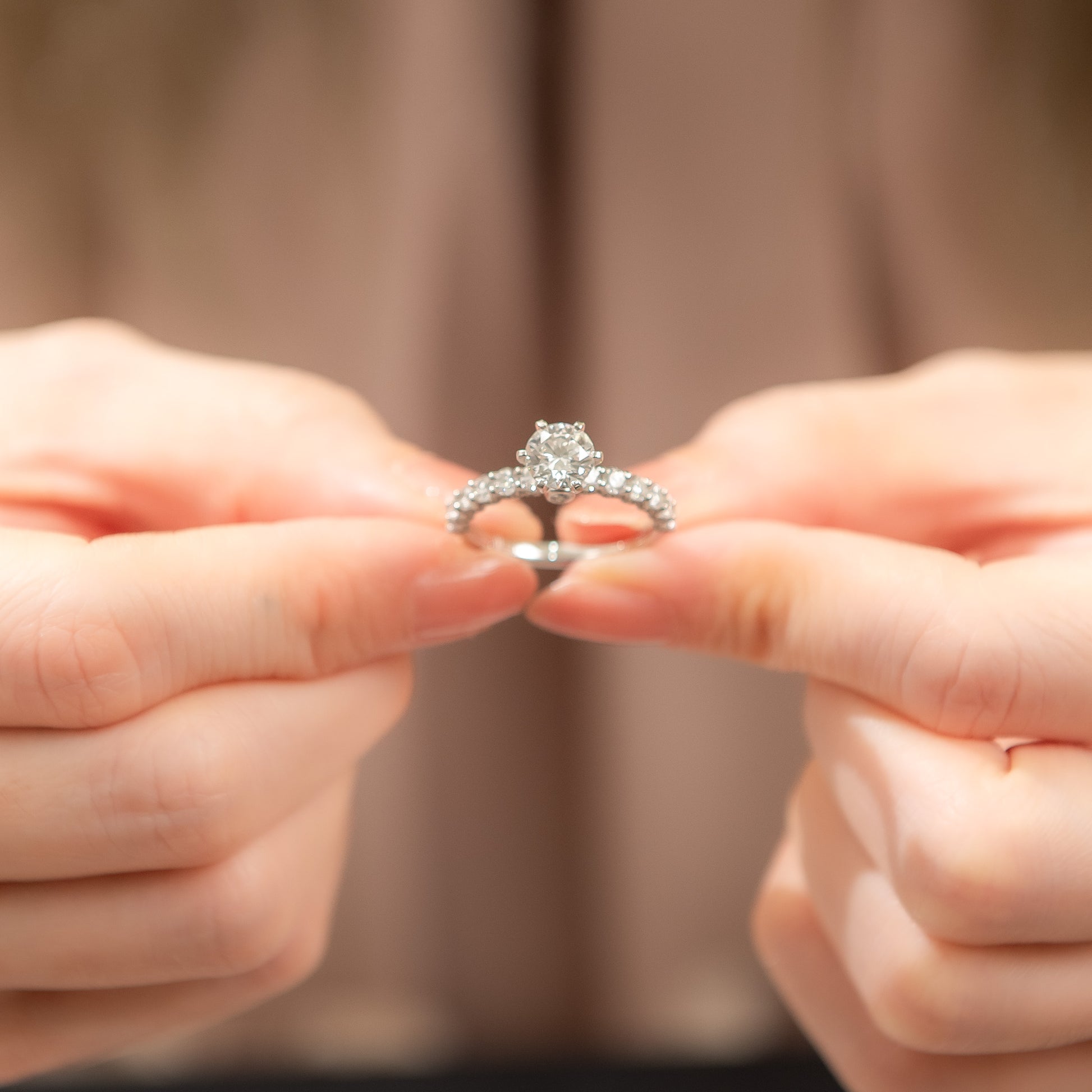 Close-up of hands holding a diamond ring against a blurred background