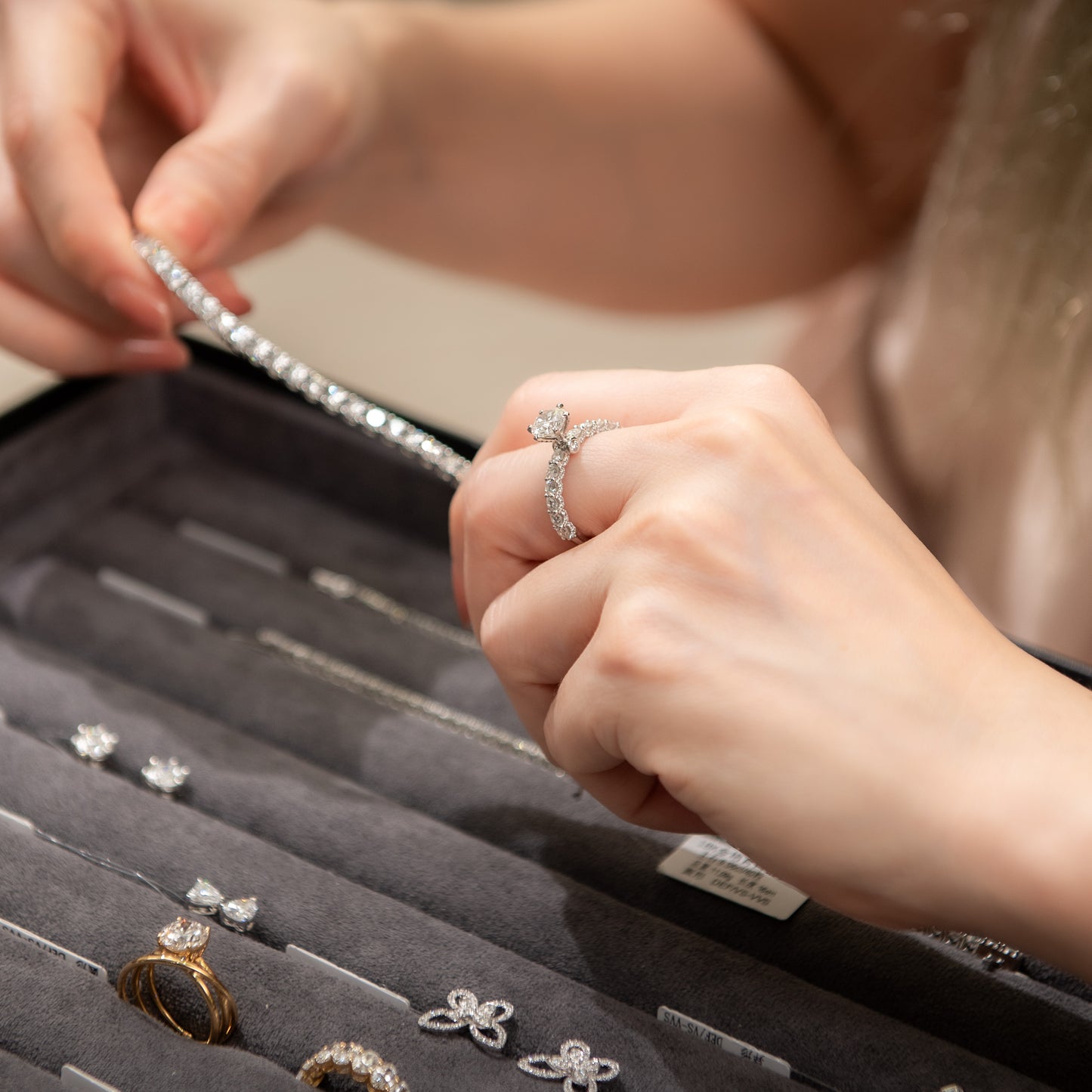 Person holding a silver ring with a close-up of jewelry in an open box.