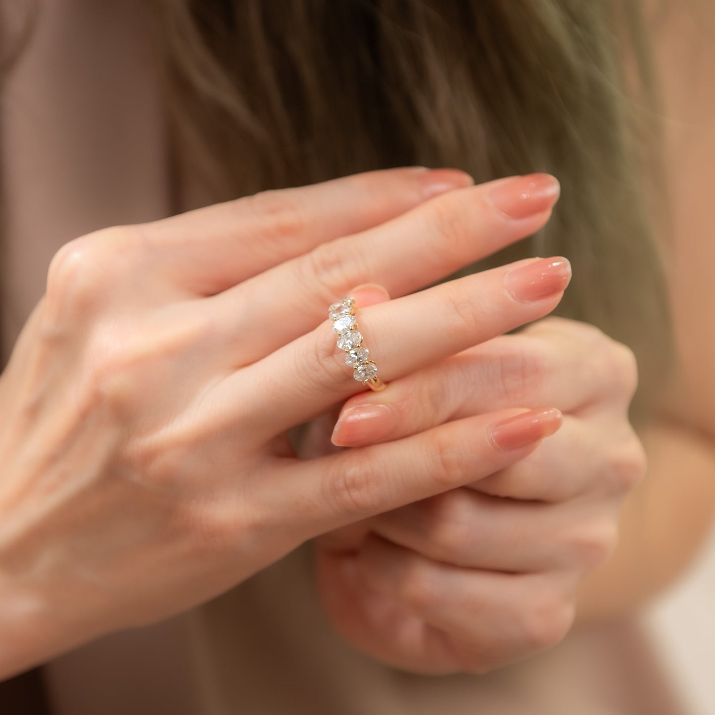 Close-up of a hand wearing a diamond ring with a blurred background