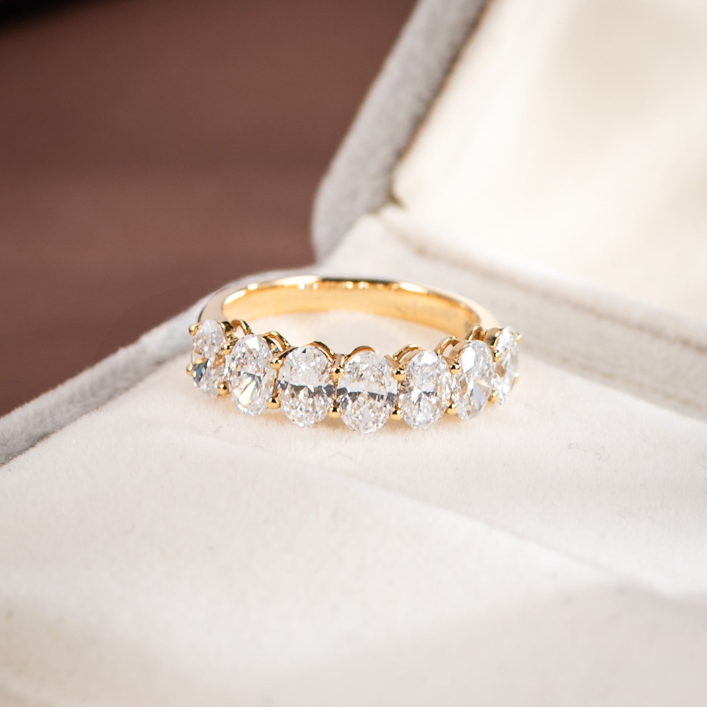 Gold ring with clear gemstones on a white cushion