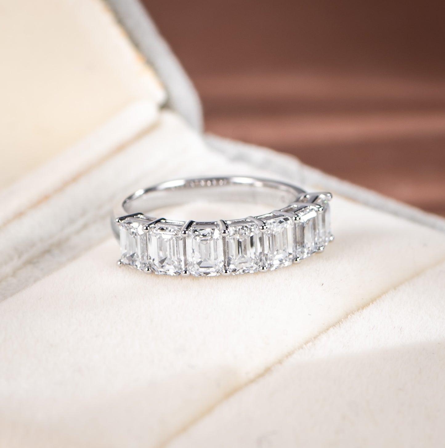 Diamond ring with emerald-cut stones on a soft background