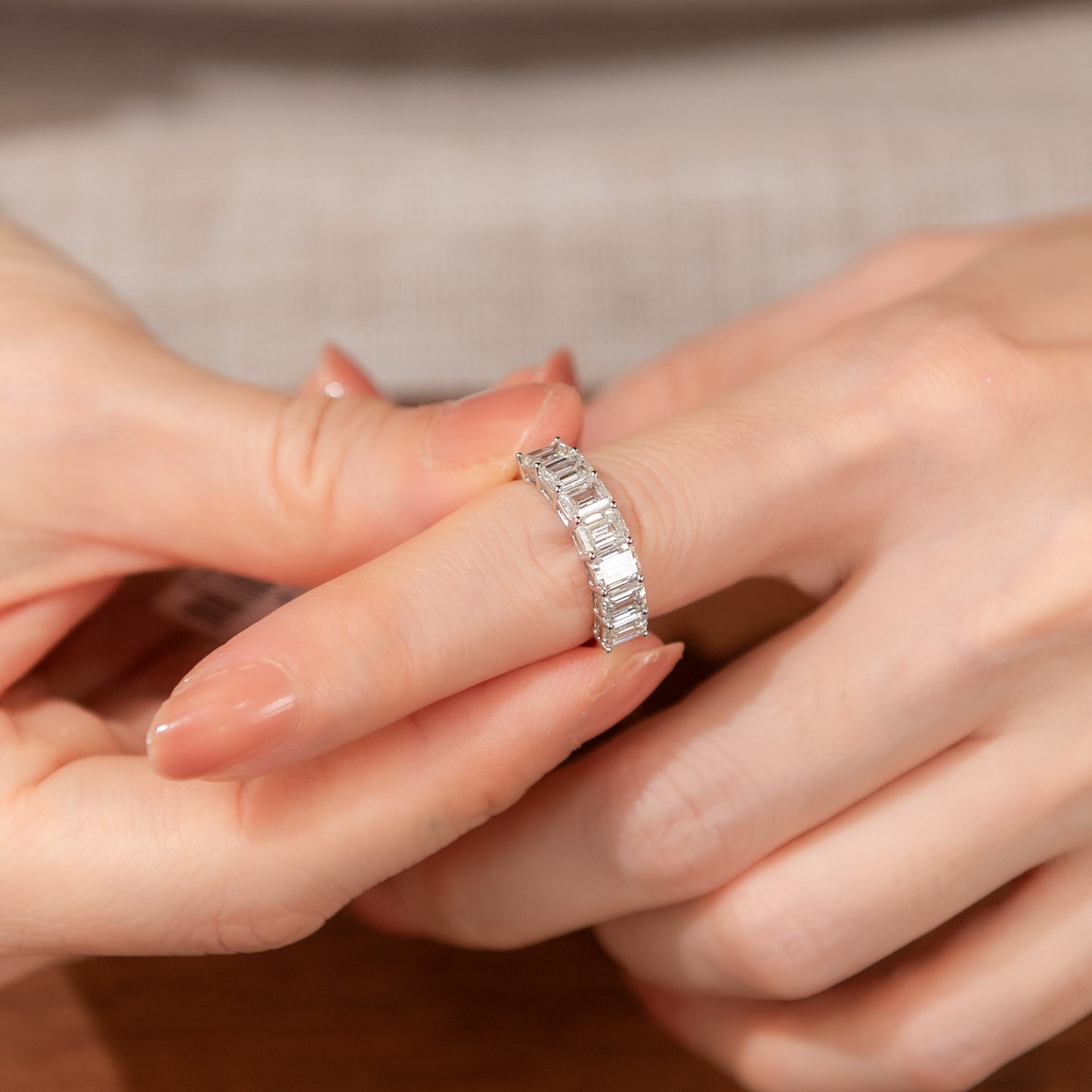Close-up of a hand wearing a diamond ring with a neutral background