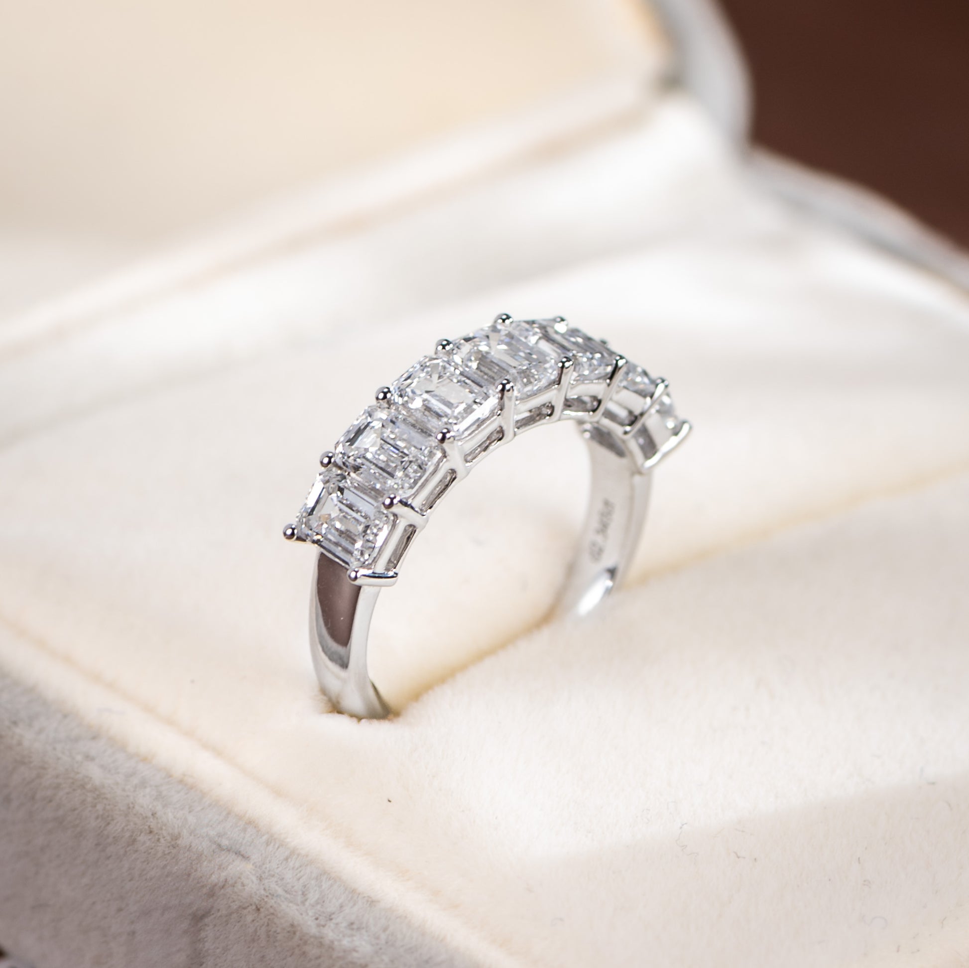 Silver ring with emerald-cut diamonds on a soft fabric background