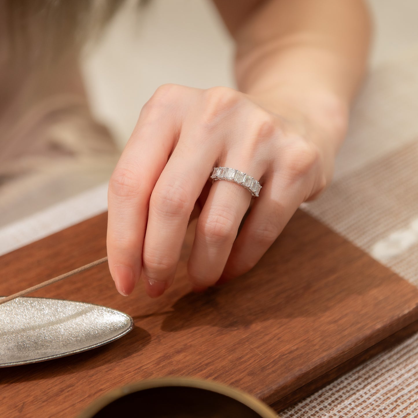 Hand wearing a diamond ring on a wooden surface