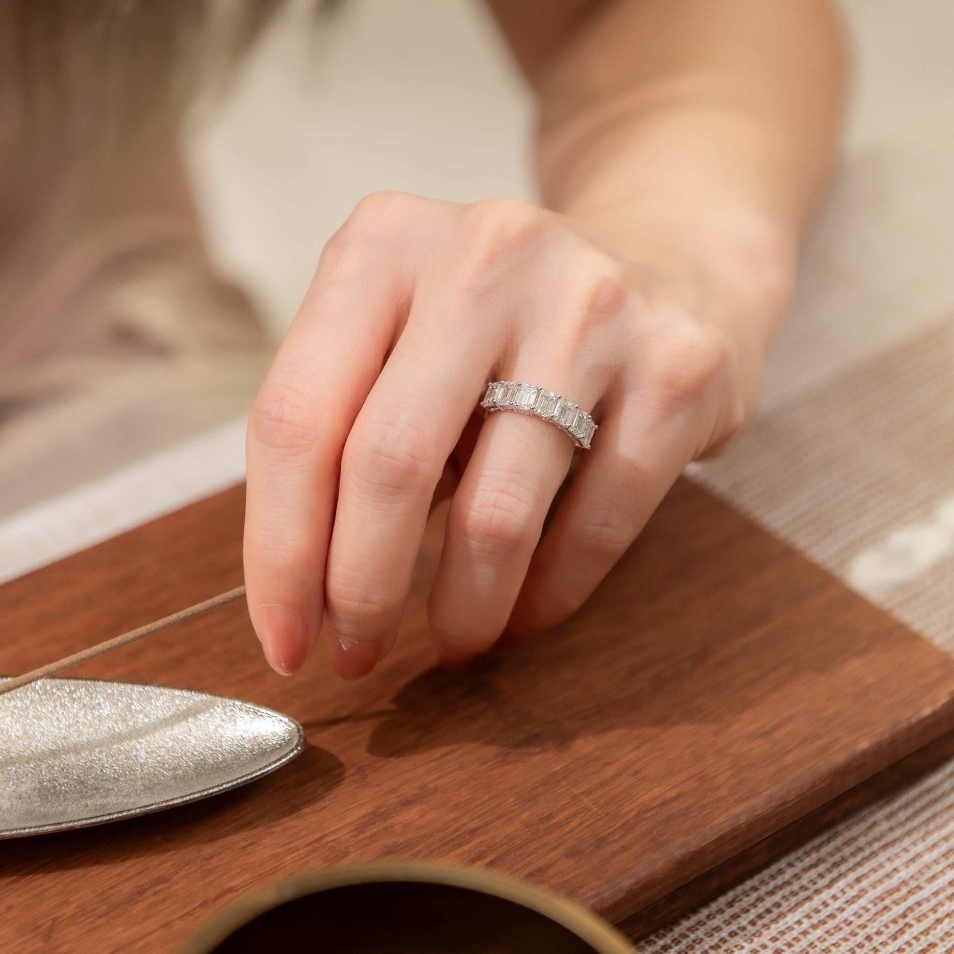 Hand wearing a diamond ring on a wooden surface