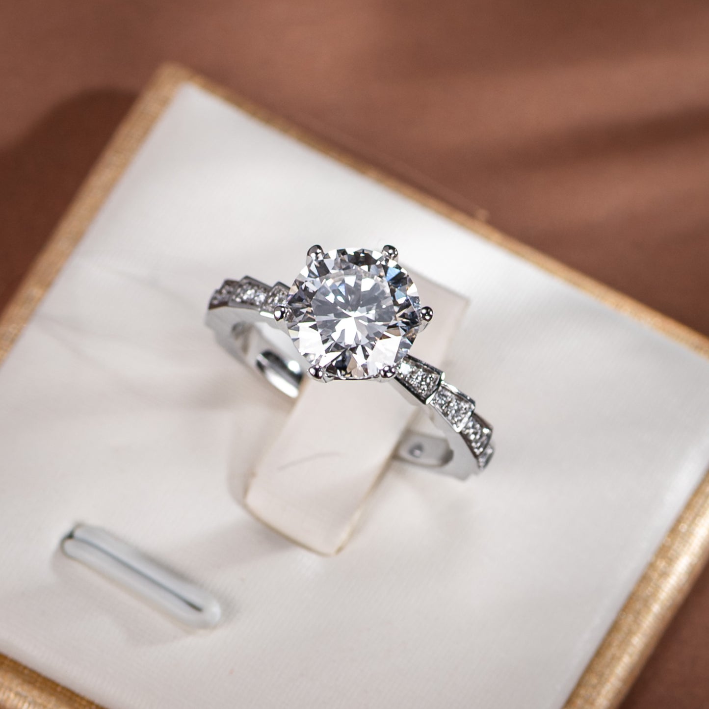 Diamond ring in a jewelry box on a brown surface