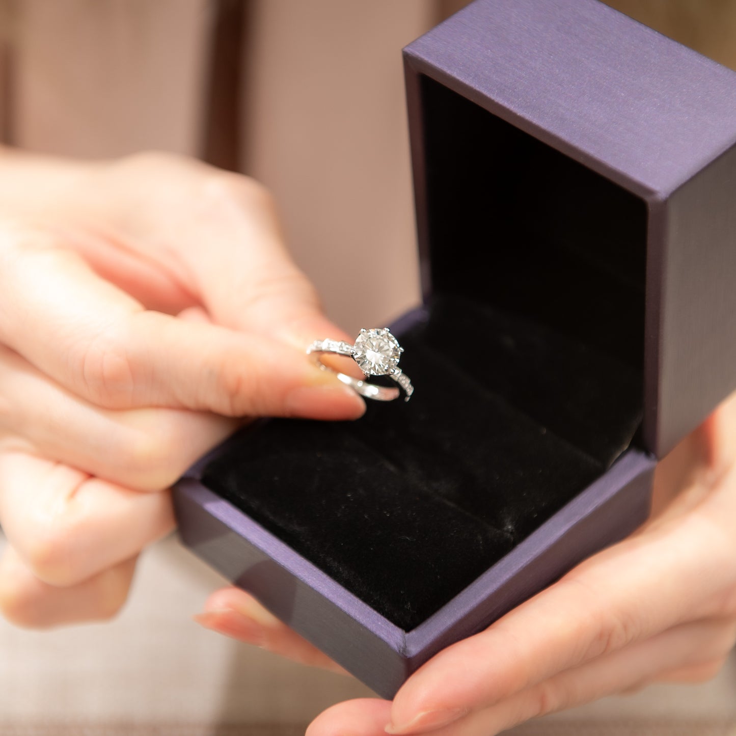 Diamond ring in an open jewelry box held by a person.