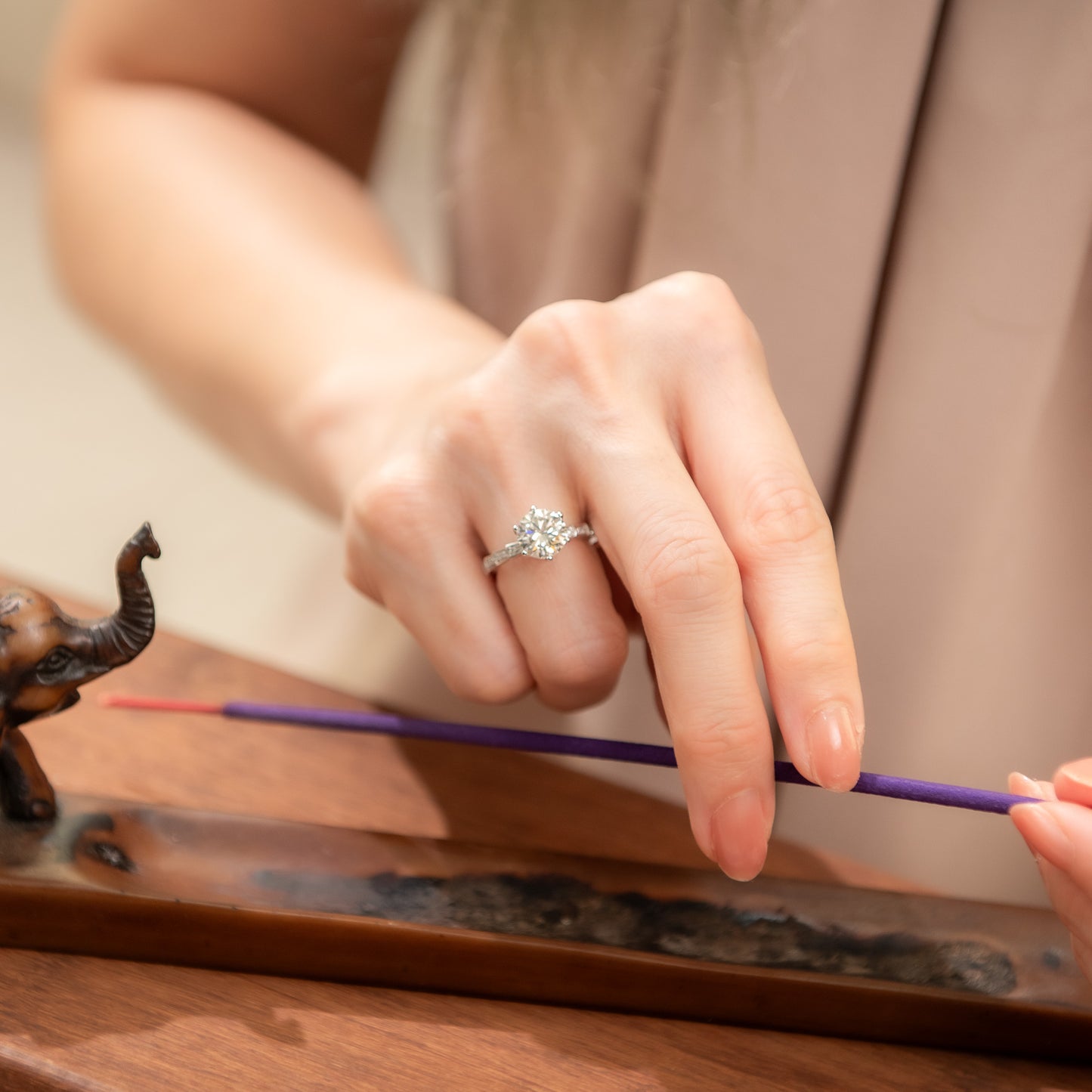 Person holding a purple incense stick with a blurred background