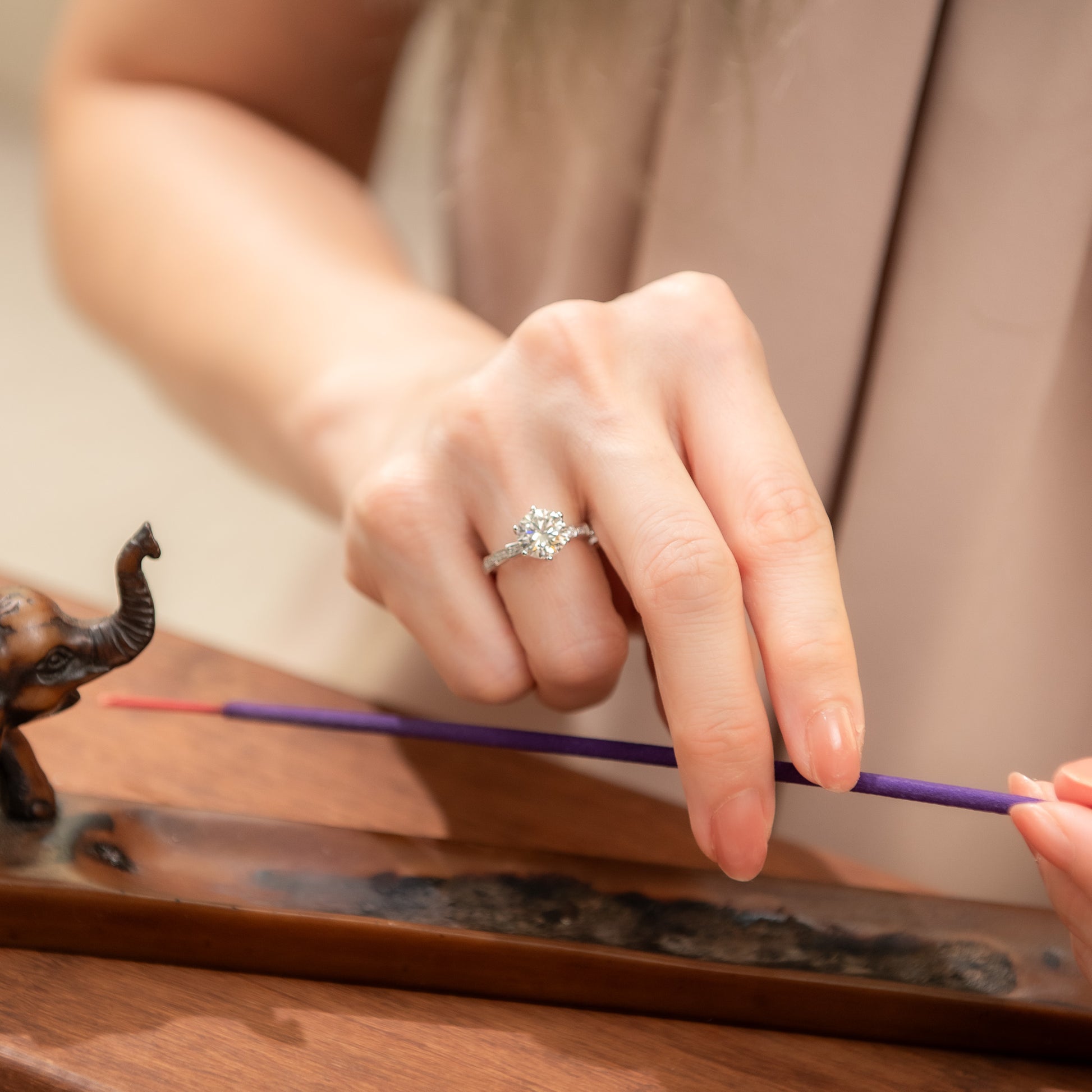 Person holding a purple incense stick with a blurred background