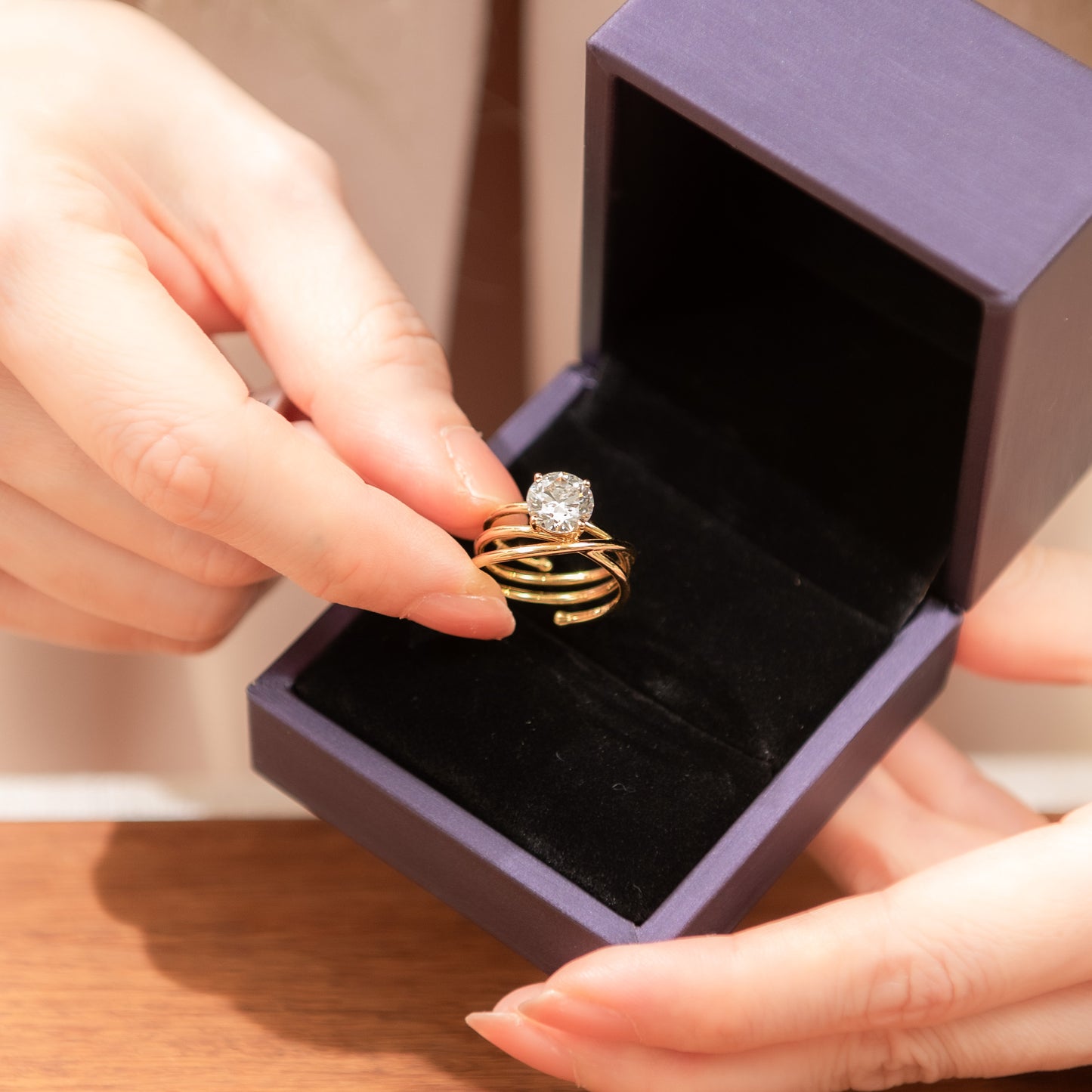 Gold ring with a diamond held above an open jewelry box