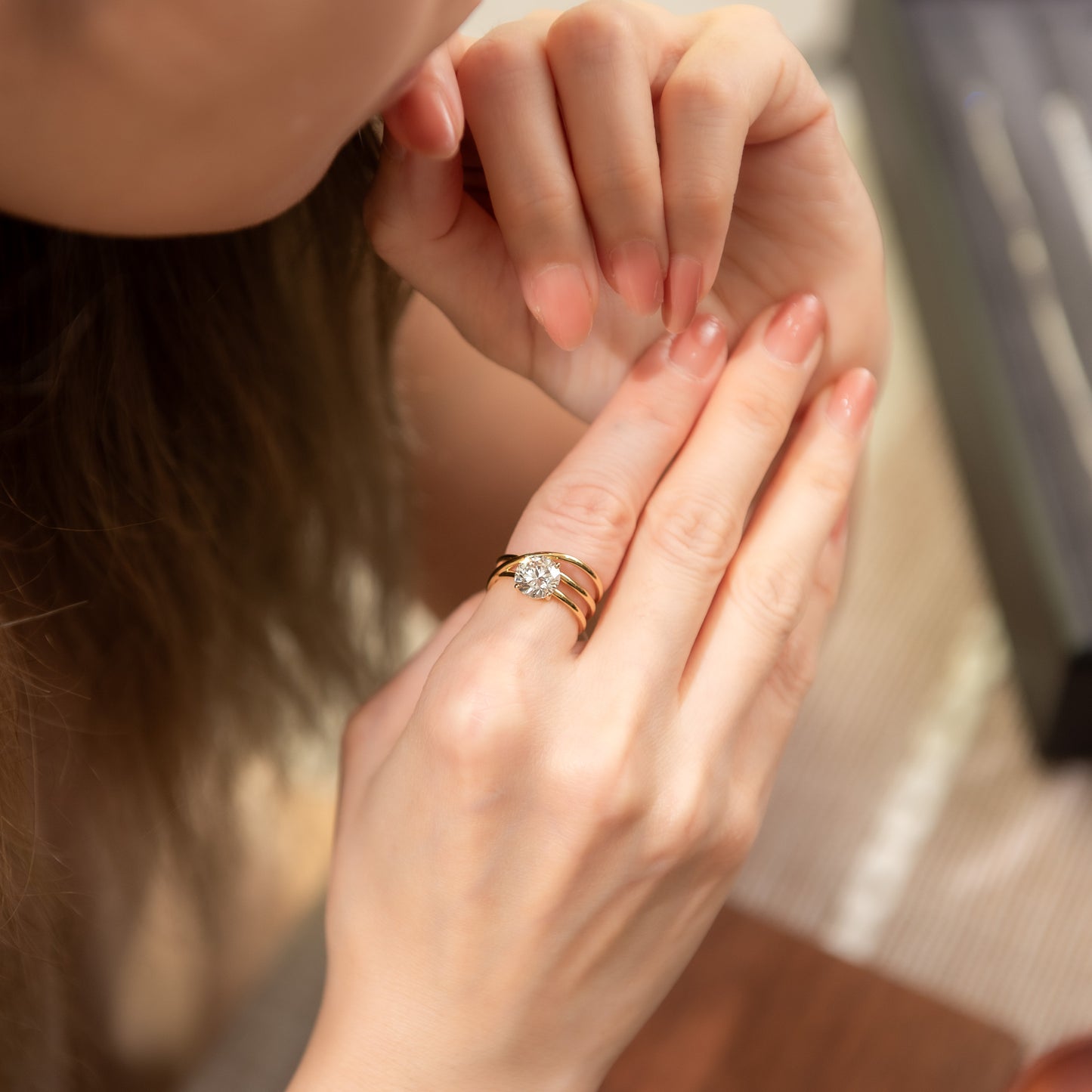 Close-up of a hand wearing a diamond ring with a blurred background