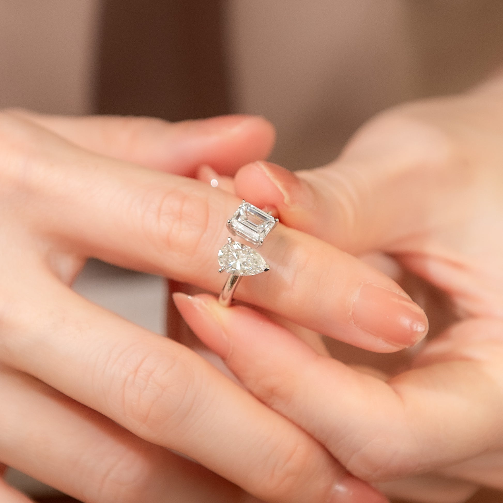 Close-up of hands wearing diamond rings on a neutral background