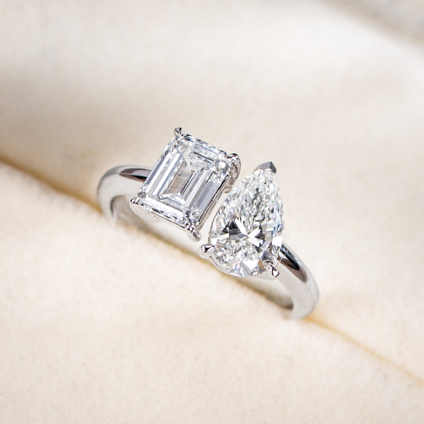 Diamond ring with two prominent diamonds on a soft beige background