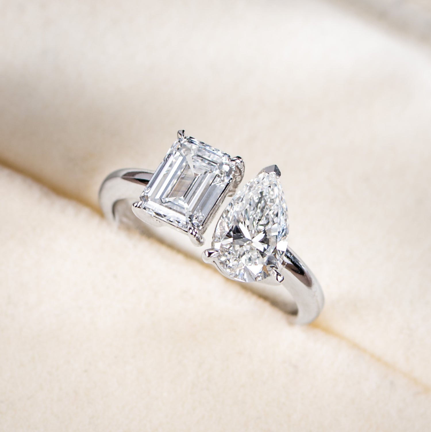 Diamond ring with two prominent diamonds on a soft beige background