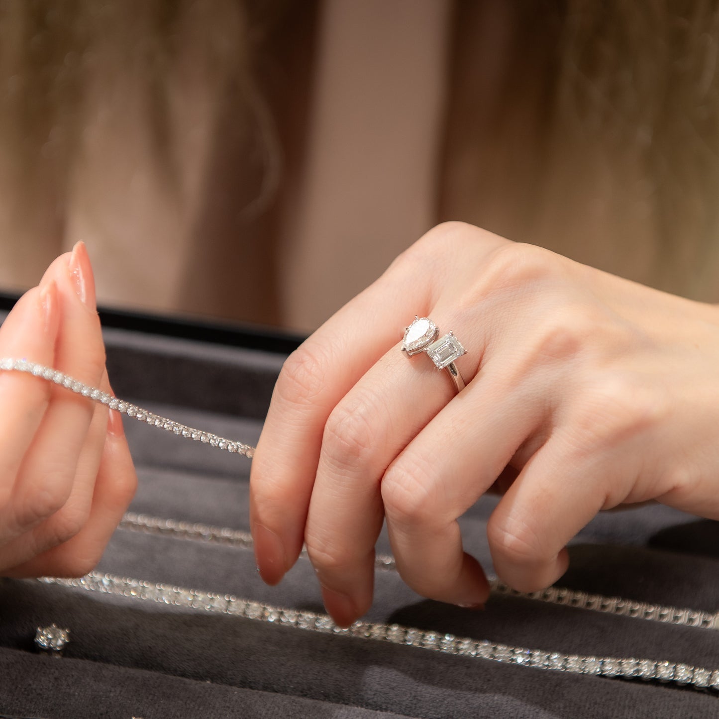 Close-up of hands wearing diamond rings on a dark surface