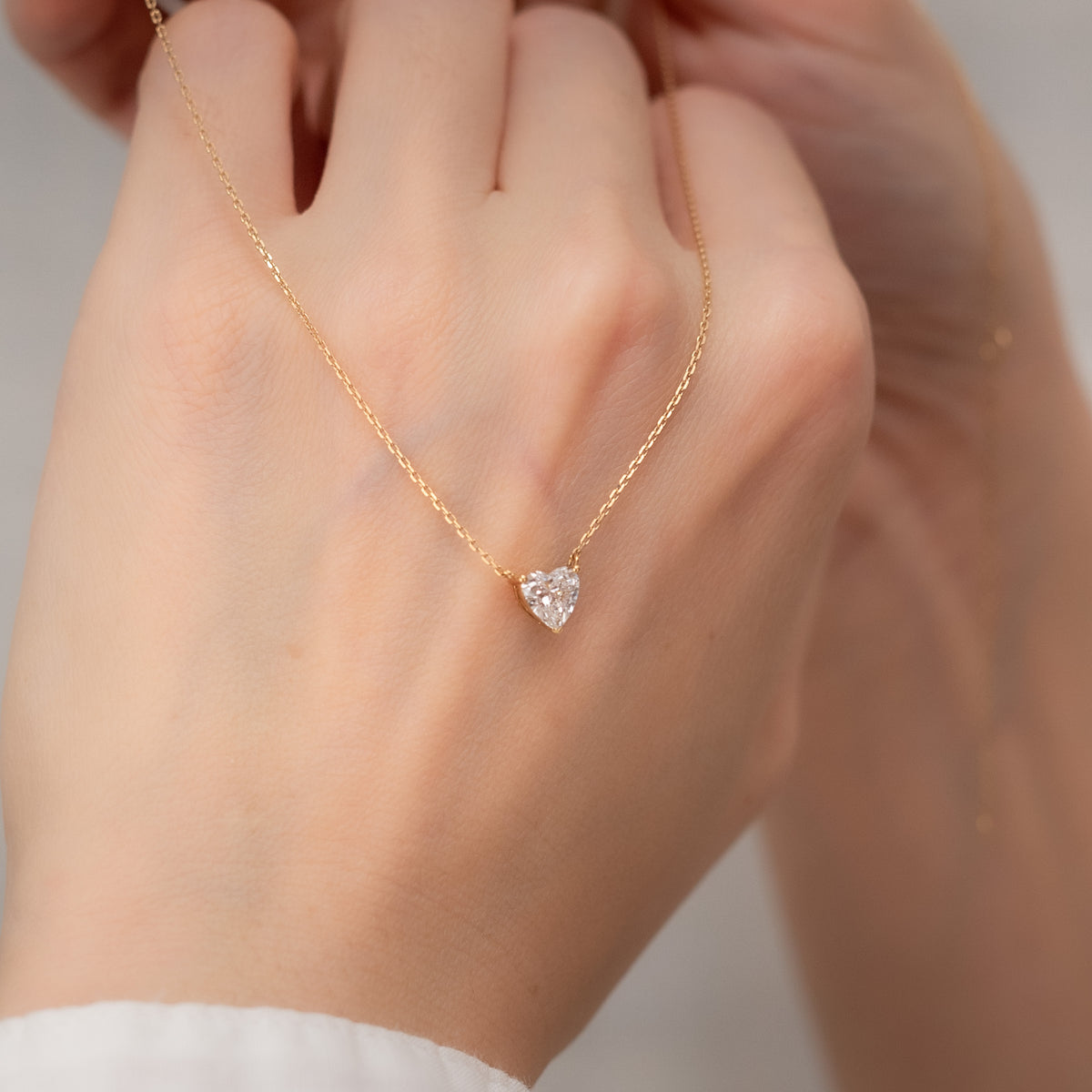 Aurora heart lab-grown diamond pendant and gold chain held in hand